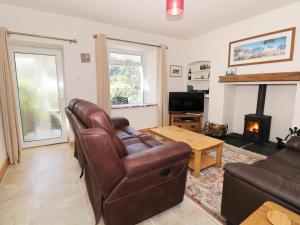 a living room with a leather couch and a fireplace at Fellview in Glenridding