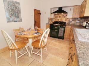 uma cozinha com uma mesa, cadeiras e um fogão em Fellview em Glenridding