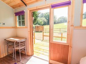 una puerta que da a una habitación con una mesa y una ventana en Railway Carriage en Abergavenny