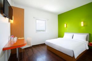a bedroom with a bed and a desk and a green wall at Amaris Hotel Ponorogo in Ponorogo