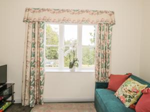 uma sala de estar com uma janela e um sofá verde em Newbiggin Cottage em Blanchland