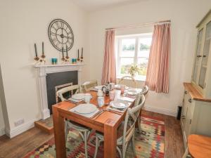 een eettafel met stoelen en een klok aan de muur bij Newbiggin Cottage in Blanchland