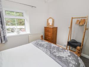 um quarto com uma cama, um espelho e uma cadeira em Ty Coed em Llanberis
