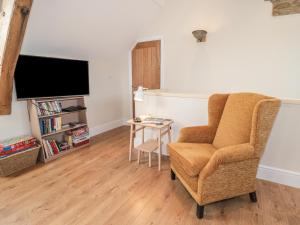 ein Wohnzimmer mit einem Stuhl und einem TV in der Unterkunft The Hay Loft in Durham