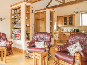 uma sala de estar com cadeiras de couro e uma cozinha em The Cottage em Watchet