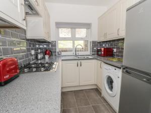 a kitchen with white cabinets and a washer and dryer at 22 Uppergate Street in Conwy