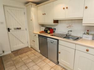 a kitchen with white cabinets and a sink and a dishwasher at Latterbarrow in Ambleside