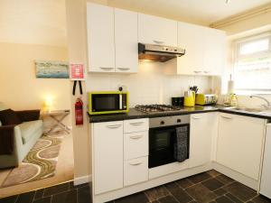 a kitchen with white cabinets and a microwave at Enginefield in Ilfracombe