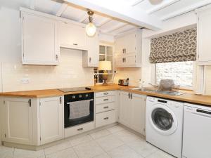 eine Küche mit weißen Schränken, einer Waschmaschine und einem Trockner in der Unterkunft Mill Leat in Castleton