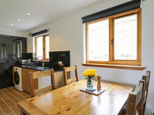 una cocina con una mesa de madera con un jarrón de flores. en The Ben, en Leckmelm