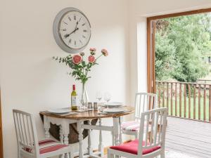 a table with chairs and a clock on the wall at Old Hall Barn 1 in Church Stretton