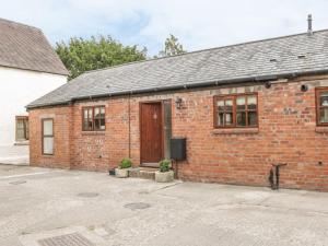 un edificio de ladrillo rojo con puerta de madera en Old Hall Barn 1, en Church Stretton