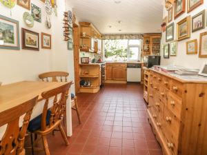 a kitchen with wooden cabinets and a table with chairs at Woolly Welcome in Penzance