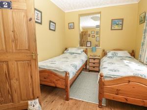 1 Schlafzimmer mit 2 Einzelbetten und einem Spiegel in der Unterkunft Woolly Welcome in Penzance