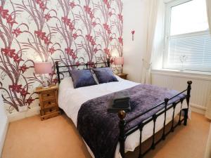 a bedroom with a bed with a floral wallpaper at The Old School House in Bala