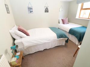 two beds in a room with white walls at The Granary in Lydney