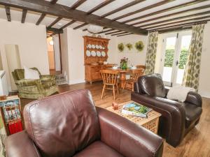 uma sala de estar com um sofá de couro e uma mesa em Barn Cottage em Buxton