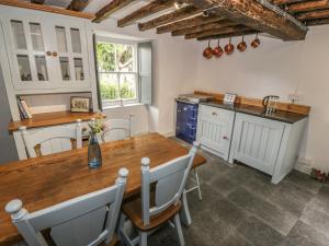 a kitchen with a wooden table and a sink at College Cottage in Corwen