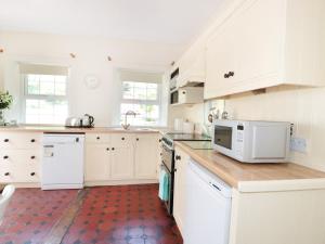 uma cozinha branca com armários brancos e um micro-ondas em School House em Builth Wells