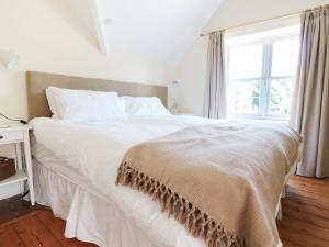 uma cama branca num quarto com uma janela em School House em Builth Wells