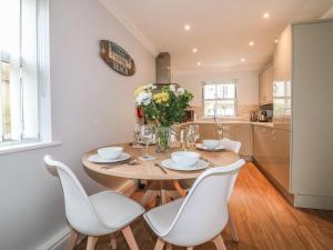 a kitchen with a wooden table and white chairs at 7 The Retreat in Paignton