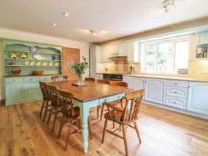 uma cozinha com uma mesa de madeira e cadeiras em Wood View Cottage em Blackawton