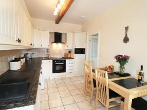 uma cozinha com armários brancos e uma mesa e cadeiras em Street House Farm Cottage em Saltburn-by-the-Sea