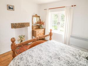 a bedroom with a bed and a mirror and a window at Callow Cottages in Ashbourne