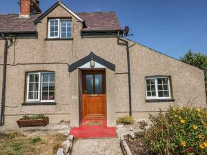 a brick house with a brown door and a red rug at No 2 New Cottages in Pembroke
