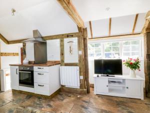 cocina con armarios blancos y TV de pantalla plana en Barn Acre Cottage en Newquay