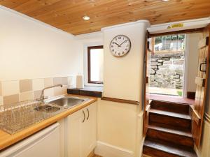 kuchnia ze zlewem i zegarem na ścianie w obiekcie Mill View Cottage w mieście Belper