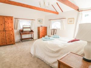 a bedroom with a bed and a desk and windows at Stable Cottage in Sudbury