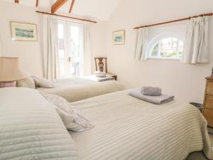 a bedroom with two beds and a window at Stable Cottage in Sudbury