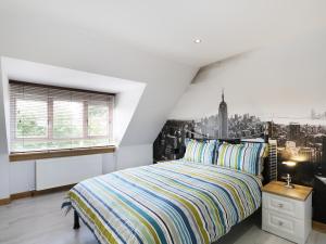 a white bedroom with a bed and a window at Maclean Cottage in Beauly