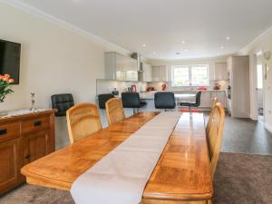 una sala da pranzo e una cucina con tavolo e sedie in legno di Burnside Cottage a Portree