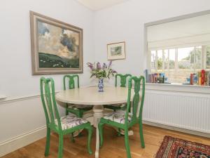 uma mesa com quatro cadeiras e um vaso com flores em Maple Cottage em Sturminster Newton