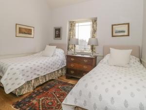 a bedroom with two beds and a window at Maple Cottage in Sturminster Newton