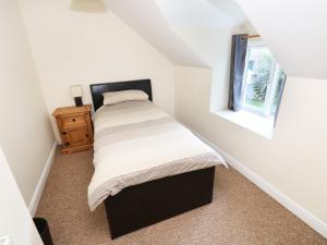 a small bedroom with a bed and a window at Llygad-yr-Haul in Pontfaen