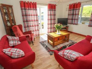 a living room with red chairs and a tv at Broadford Farm Bungalow in Kidwelly
