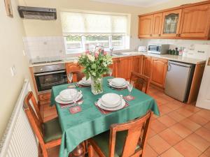 una cocina con una mesa con platos y flores. en Broadford Farm Bungalow, en Kidwelly