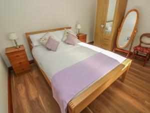 1 dormitorio con 1 cama grande y espejo en Broadford Farm Bungalow, en Kidwelly