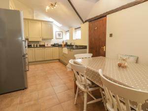 uma cozinha com uma mesa com cadeiras e um frigorífico em Oak Cottage em Wareham