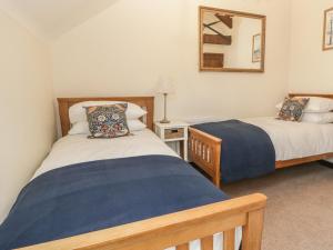 a bedroom with two beds and a mirror at Oak Cottage in Wareham