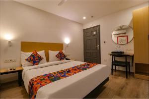 a hotel room with a bed and a desk and a door at FabHotel Hargobind Enclave in New Delhi