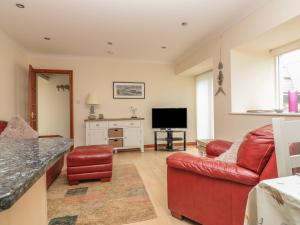 a living room with a red couch and a television at Sorrel Cottage in Padstow