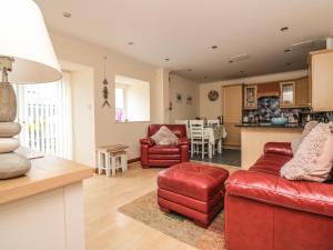 a living room with red furniture and a kitchen at Sorrel Cottage in Padstow