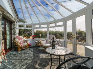 a conservatory with a glass roof with a table and chairs at Sheila's Cottage in Penryn