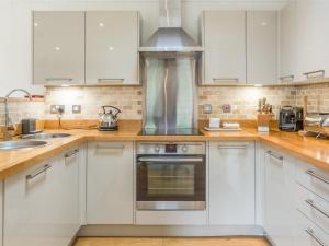 Una cocina con gabinetes blancos y un horno de estufa. en 7 Water's Edge, en Looe 14 fotos más