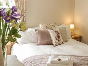 a white bed with pillows and a vase of flowers at 31 Riverside in Bridgnorth