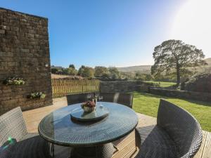 a patio with a table and chairs on a deck at The Cottage, Beeston Hall in Sowerby Bridge